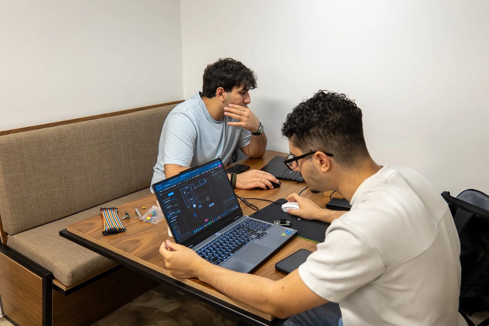 Two participants working on a circuit layout with hardware beside their laptops